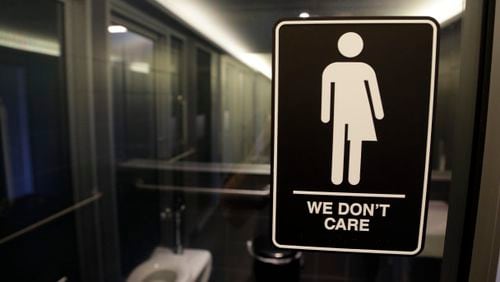 A sign is seen outside a restroom at 21c Museum Hotel in Durham, N.C. The state is in a legal battle over a state law that requires transgender people to use the public restroom matching their biological sex. The ADA-compliant bathroom signs were designed by artist Peregrine Honig. (AP Photo/Gerry Broome)