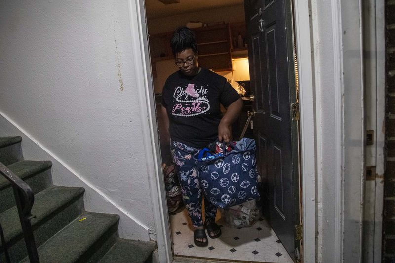 Tranisha Wilcox carries trash bags, totes and laundry baskets stuffed with her family's belongings to her car on the evening she moved out of Pavilion Place. She could not find an apartment that she could afford by her eviction deadline, so in October, she and her two sons moved to a hotel off Fulton Industrial Boulevard in southwest Fulton County. (Alyssa Pointer / AJC 2021)