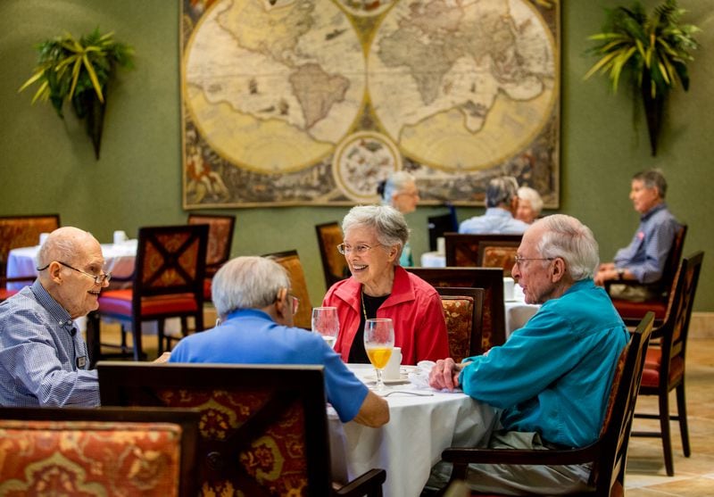 Residents at Canterbury Court including Clyde May, from left, Fritz Tourssaint, back to camera, Barbara Cheshire and Clyde Herron finish up their lunch in the dining room at Canterbury Court. During the worst of the pandemic, meals were delivered to their apartments and visitors were not allowed.  (Jenni Girtman for The Atlanta Journal Constitution)
