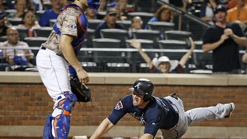 New York Mets catcher Travis d'Arnaud watches without a ball to make the tag as Atlanta Braves Chris Johnson, right, dives into the plate to score on Christian Bethancourt's eighth-inning, softly-hit RBI single in a baseball game in New York, Monday, July 7, 2014.
