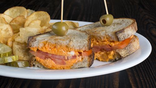 Peach & The Porkchop’s grilled pimento cheese sandwich is served with tomato on sourdough bread, alongside house-made chips. / Photo credit: George Miko Photography