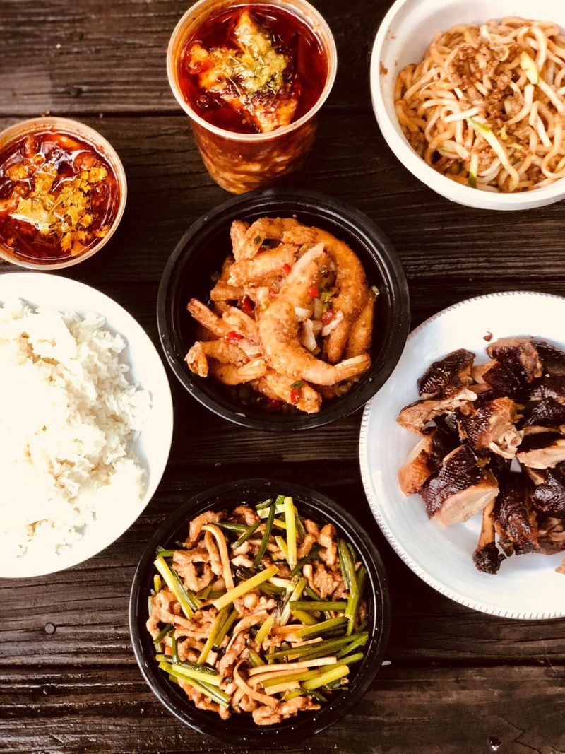 This takeout feast from Great Sichuan includes (from upper right): zhajiangmian (noodles with ground pork, cucumber and fermented soybean sauce); tea-smoked duck; pork with chive flowers; white rice; spicy boiled fish fillets (two containers); and salt and pepper shrimp (center). CONTRIBUTED BY WENDELL BROCK