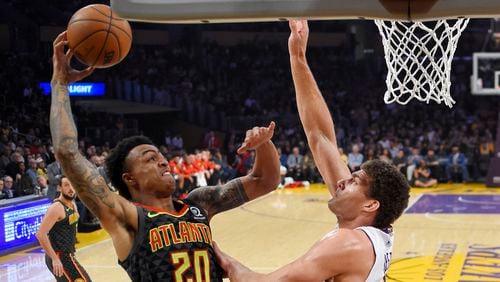 Atlanta Hawks forward John Collins, left, shoots as Los Angeles Lakers center Brook Lopez defends during the first half of a basketball game, Sunday, Jan. 7, 2018, in Los Angeles. (AP Photo/Mark J. Terrill)