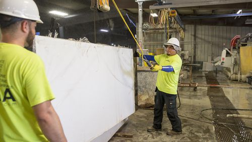 At Newnan-based fabrication firm- Mega Granite & Marble, employees prepare a slab for cutting.