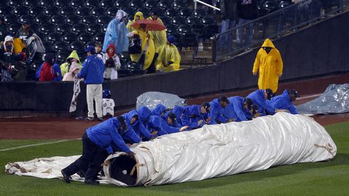 The Citi Field grounds crew rolls out the tarp to cover the field in a heavy rain before the ninth inning with the score tied at 5-5 in a baseball game between the Atlanta Braves and the New York Mets at Citi Field in New York, Friday, May 24, 3013. (AP Photo/Paul J. Bereswill)