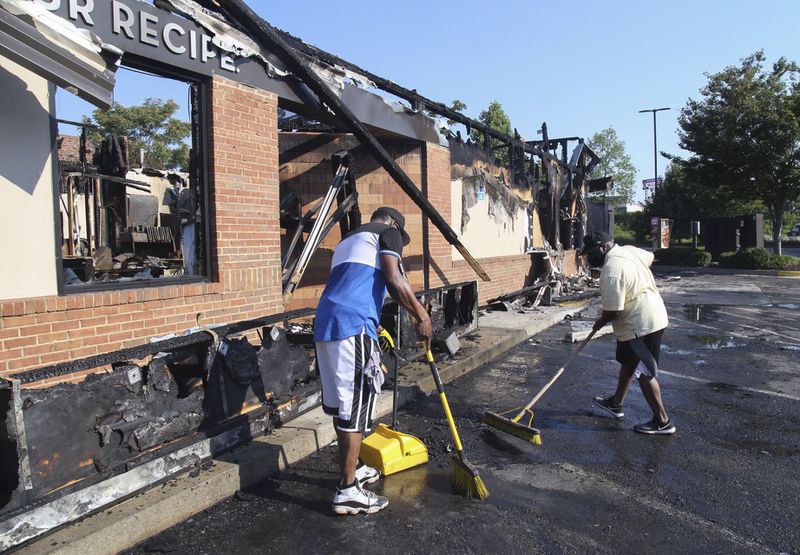 Renault Verona (left) and other area residents came on their own to help clean up Sunday after a fire gutted the Wendy’s where Rayshard Brooks was shot.