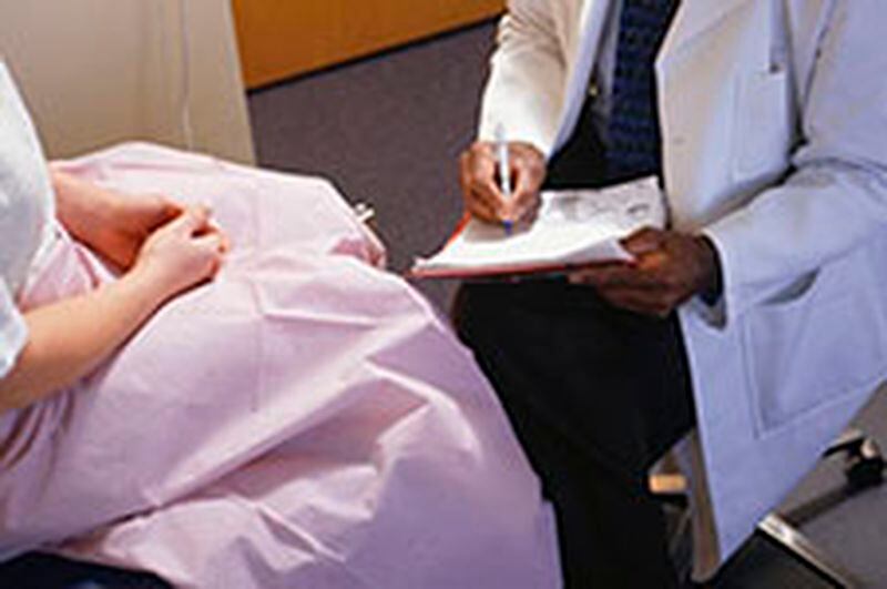 Doctor filling in gynaecological chart, close-up, mid section, elevated view