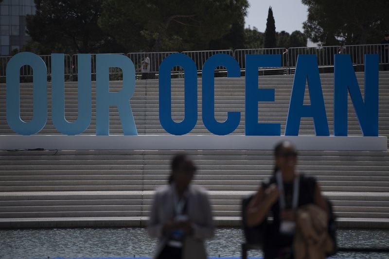 People walk in front of an 'Our Ocean' sign during the 'Our Ocean Conference' at the Stavros Niarchos Foundation Cultural Center in Athens, Greece, Tuesday, April 16, 2024. Greece aims to create two large marine parks as part of a 780 million euro ($830 million) program to protect biodiversity and marine ecosystems, with the plans to be formally announced at an international oceans conference starting in Athens Tuesday. (AP Photo/Michael Varaklas)