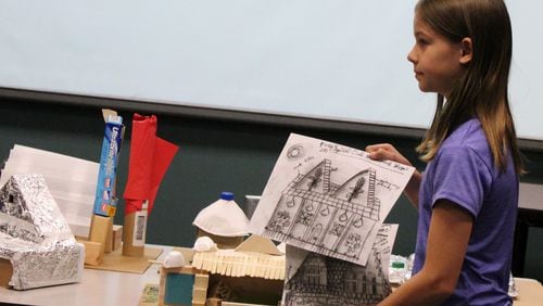 Student Eleni Witte shows off her designs for the Spiral Oak Hammock Shop, a project she created as part of the Cobb County Public Library system s Discover Architecture series. Photo by Tom Brooks.
