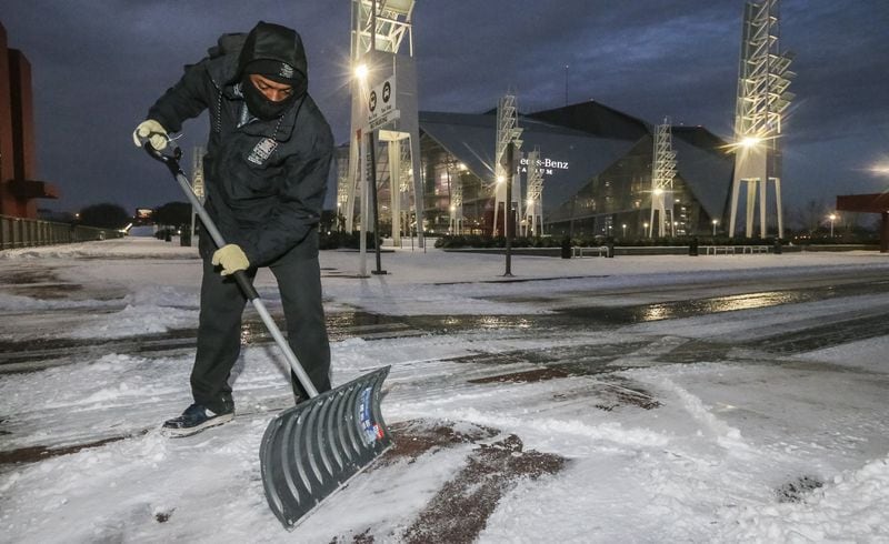 Melvin Tucker braved the cold to remove snow and ice at the Georgia World Congress Center on Wednesday.  JOHN SPINK/JSPINK@AJC.COM