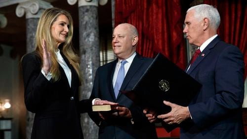 Sen. Kelly Loeffler, R-Ga., left, with her husband Jeffrey Sprecher, center, participates in a re-enactment of her swearing-in Monday Jan. 6, 2020, by Vice President Mike Pence in the Old Senate Chamber on Capitol Hill in Washington. (AP Photo/Jacquelyn Martin)