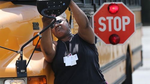 March 28, 2017, Stone Mountain: Bus driver Felicia Evans adjusts a side view mirror while performing a safety check on her bus before leaving the Gregory K. Davis Fleet Service Center at the DeKalb Schools Headquarters to make her afternoon run on Tuesday, March 28, 2017, in Stone Mountain.   Curtis Compton/ccompton@ajc.com