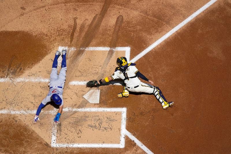 Chicago Cubs' Dansby Swanson slides safely past Milwaukee Brewers catcher Victor Caratini during the second inning of a baseball game Monday, July 3, 2023, in Milwaukee. (AP Photo/Morry Gash)