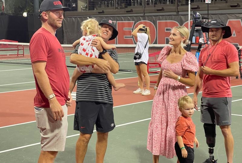 Georgia women's tennis coach Jeff Wallace holds one of his four grandchildren as son-in-law, Chris Sjogren (L), daughter, Brittany Sjogren and son, Jarryd Wallace talk before leaving the court Henry Feild Stadium following the last home match of Wallace's 38-year career at Georgia. (Photo by Chip Towers/ctowers@ajc.com)