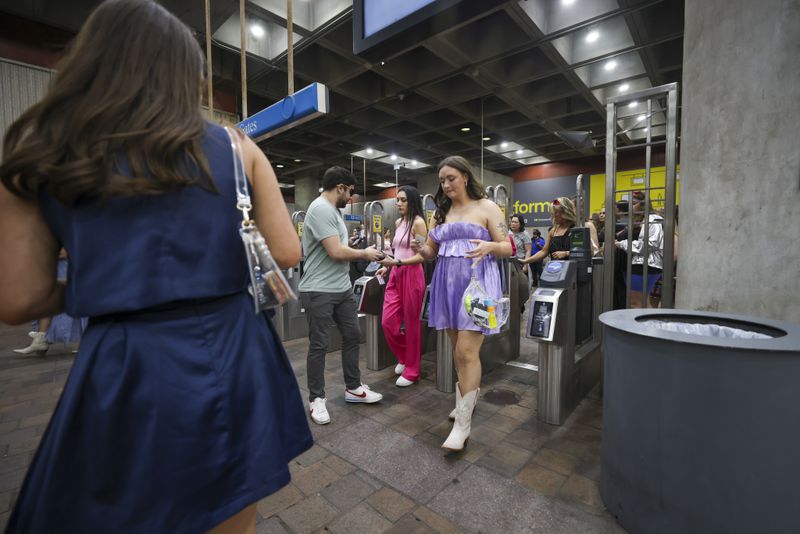 Fans of Taylor Swift use their breeze cards to get out of the gates of the GWCC MARTA station as they move toward Mercedes-Benz Stadium before the Taylor Swift concert Friday in Atlanta. Taylor Swift and Janet Jackson performed next door to one another Friday night, Jackson at State Farm Arena and Swift at Mercedes-Benz Stadium. 