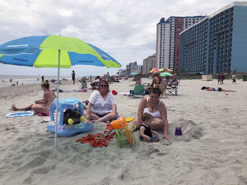 Christy Kasler, center, from Ohio, enjoys a day at the beach,  while her daughter-in-law Cory plays with her grandson, Bentley, in Myrtle Beach.