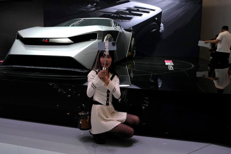 A live streamer poses near a concept car from Nissan during Auto China 2024 held in Beijing, Thursday, April 25, 2024. Global automakers and EV startups unveiled new models and concept cars at China's largest auto show on Thursday, with a focus on the nation's transformation into a major market and production base for digitally connected, new-energy vehicles. (AP Photo/Ng Han Guan)