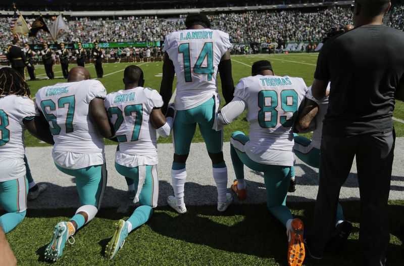 Miami Dolphins offensive tackle Laremy Tunsil (67), Maurice Smith (27), Jarvis Landry (14) lock hands with teammates during the playing of the national anthem before an NFL football game against the New York Jets Sunday, Sept. 24, 2017, in East Rutherford, N.J. (AP Photo/Seth Wenig)