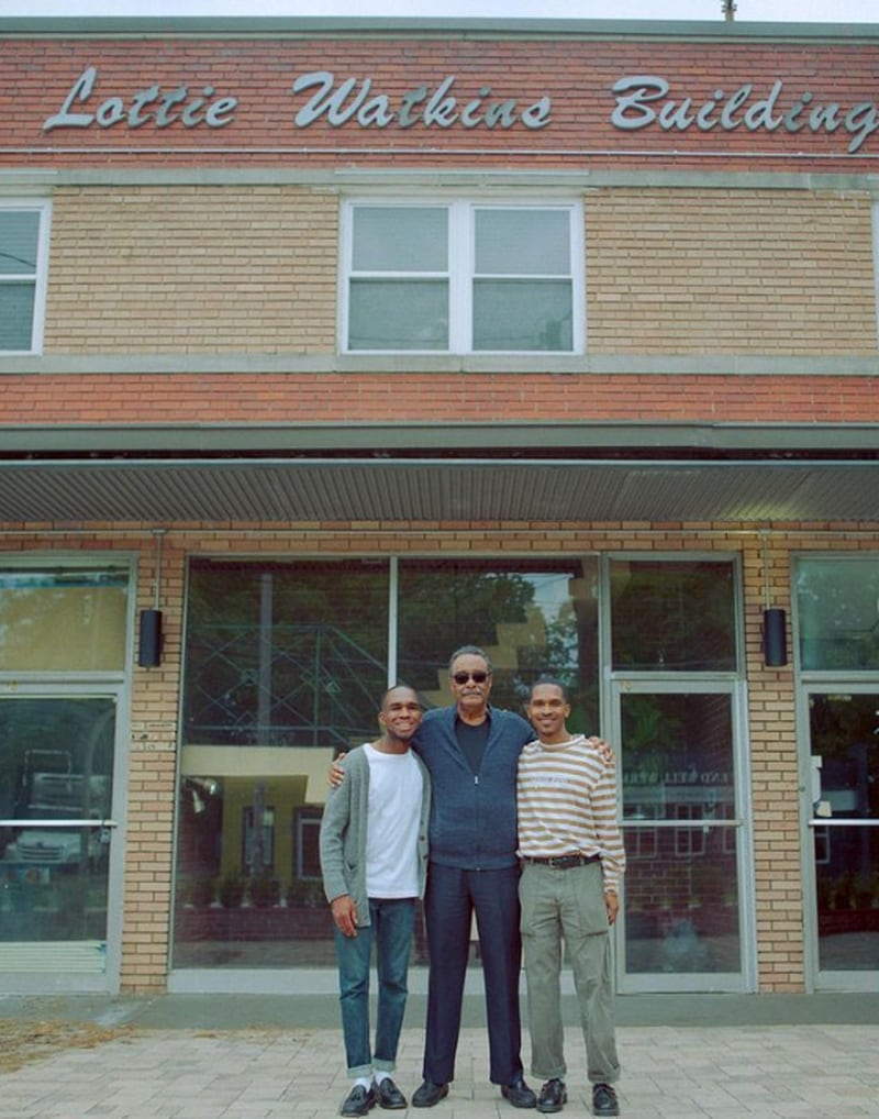 Portrait Coffee co-owner Aaron Fender (left) with Lottie Watkins' brother-in-law (center) and Portrait co-owner Marcus Hollinger (right) in front of the Lottie Watkins Building, home to Portrait Coffee. / Courtesy of Portrait Coffee