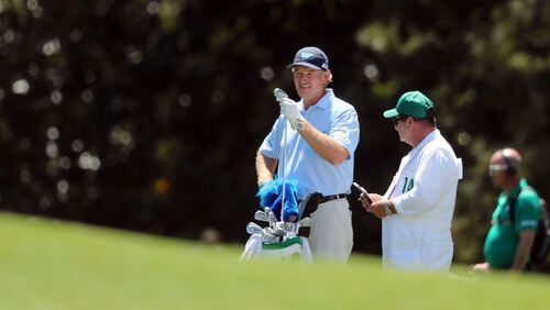 Ernie Els and his caddie, Ricci Roberts, await his shot on the 18th fairway. Els shot a 78 as the first player off the tee on Sunday. CURTIS COMPTON/ AJC
