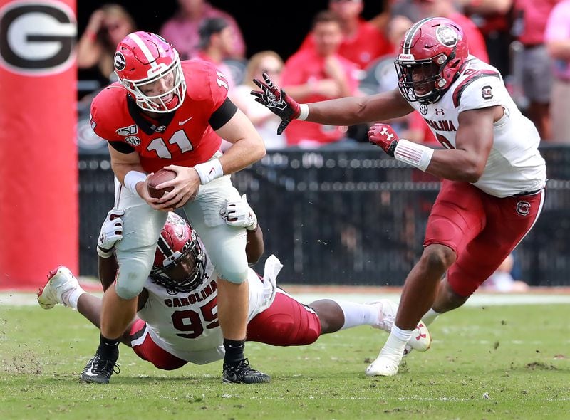 Georgia quarterback Jake Fromm is sacked by South Carolina defenders Kobe Smith (left) and D.J. Wonnum (right) during the third quarter in a NCAA college football game on Saturday, October, 12, 2019, in Athens.    Curtis Compton/ccompton@ajc.com