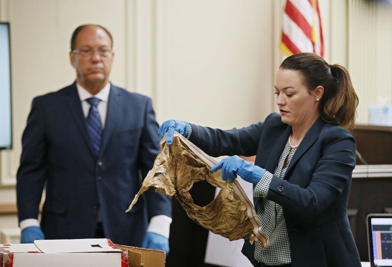 Larry Peterson (left), a former GBI forensic investigator, watches as Assistant District Attorney Marie Broder shows the jury some of victim Timothy Coggins’ clothing during the murder trial of Franklin Gebhardt on June 21, 2018, at the Spalding County Courthouse in Griffin. 