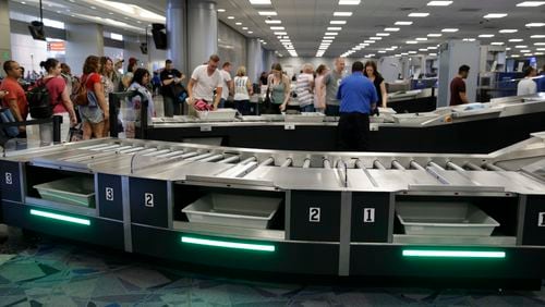 In this Sept. 1, 2017, photo, people use newly installed automated security lanes at McCarran International airport Friday, Sept. 1, 2017, in Las Vegas. Three reconfigured security lanes are equipped with upgraded features, including bins that are 25 percent larger and capable of holding roll-aboard luggage.
 (AP Photo/John Locher)