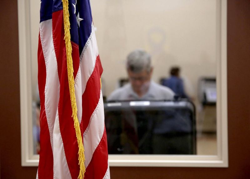 A U.S. flag stands as a voter participates Tuesday in the Georgia runoff election at the North Fulton Government Service Center in Sandy Springs. (JASON GETZ/SPECIAL TO THE AJC)