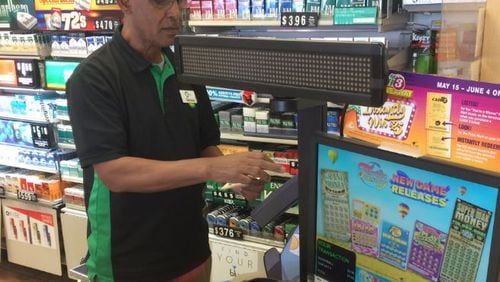 Gosaye Gebre, a cashier working Saturday at a Dunwoody convenience store, said lottery sales get brisk when the jackpot climbs. CARRIE TEEGARDIN / CTEEGARDIN@AJC.COM