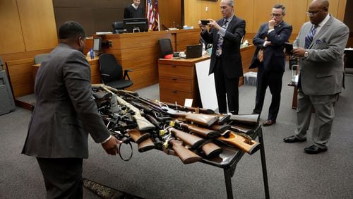 Defense attorneys Bruce Harvey at left, and Fulton County Chief Assistant District Attorney Clint Rucker, far right, take photos of a table full of Tex McIver's guns.
STEVE SCHAEFER / SPECIAL TO THE AJC
