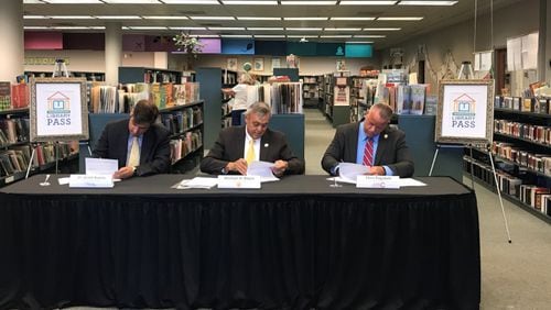 During a ceremony at the Switzer Library in Marietta on June 20, left to right, Superintendent Grant Rivera, Marietta City Schools; Chairman Mike Boyce, Cobb County Board of Commissioners and CCSD Superintendent Chris Ragsdale signed an agreement to extend the Library PASS partnership for two years. Courtesy of Cobb County School District