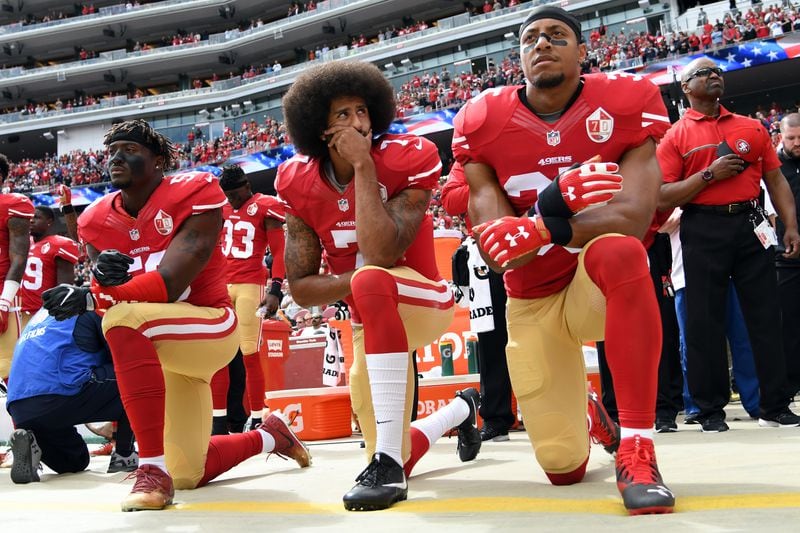 Eli Harold #58, Colin Kaepernick #7 and Eric Reid #35 of the 49ers kneel on the sideline during the national anthem prior to the game against the Cowboys at Levi's Stadium on October 2, 2016 in Santa Clara, California.