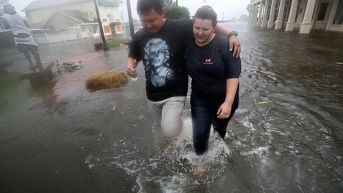 St. Marys residents Michael and Tori Munton make their way through their city's flooded streets as the storm surge from Hurricane Matthew hit on Friday. Curtis Compton /ccompton@ajc.com