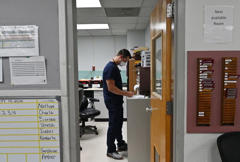 Dr. Jason Laney looks through charts at Jeff Davis Hospital in Hazlehurst. Laney said that having to call families and tell them that a loved one is not getting any better is depressing. "Every day is tragedy with COVID," he says. (Hyosub Shin / Hyosub.Shin@ajc.com)