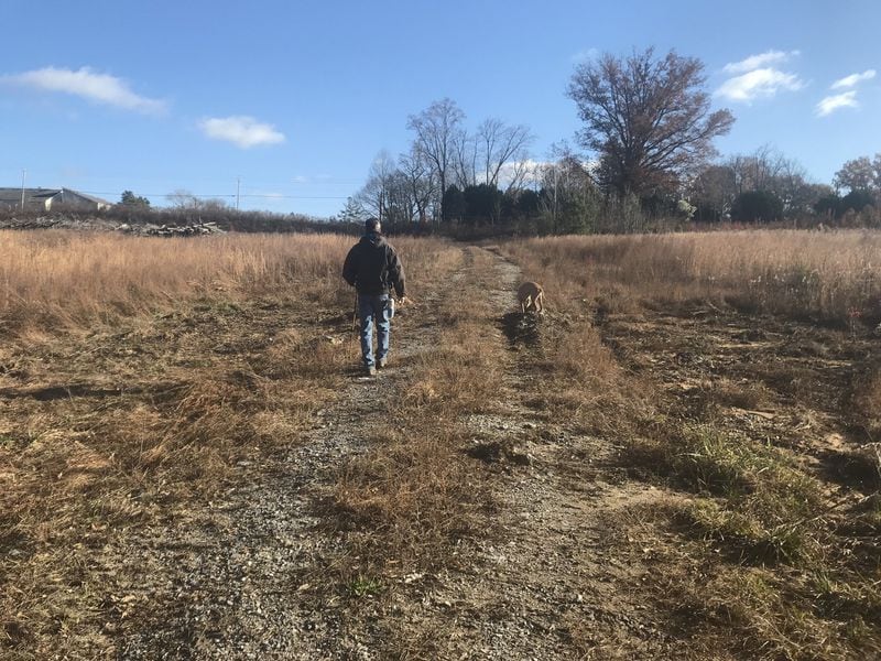 Resident Joe Peery and his dog walk on a nearby parcel of land owned by Blackhall Studios that is part of a proposed land swap with DeKalb County that would allow the company to build on a portion of the park. TIA MITCHELL/TIA.MITCHELL@AJC.COM