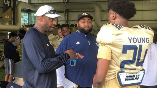 Georgia Tech defensive ends/outside linebackers coach Marco Coleman (left, in white cap) speaks with freshman defensive end Kendall Young with defensive analyst Anthony Parker looking on during a break in preseason practice August 2, 2019. (AJC photo by Ken Sugiura)