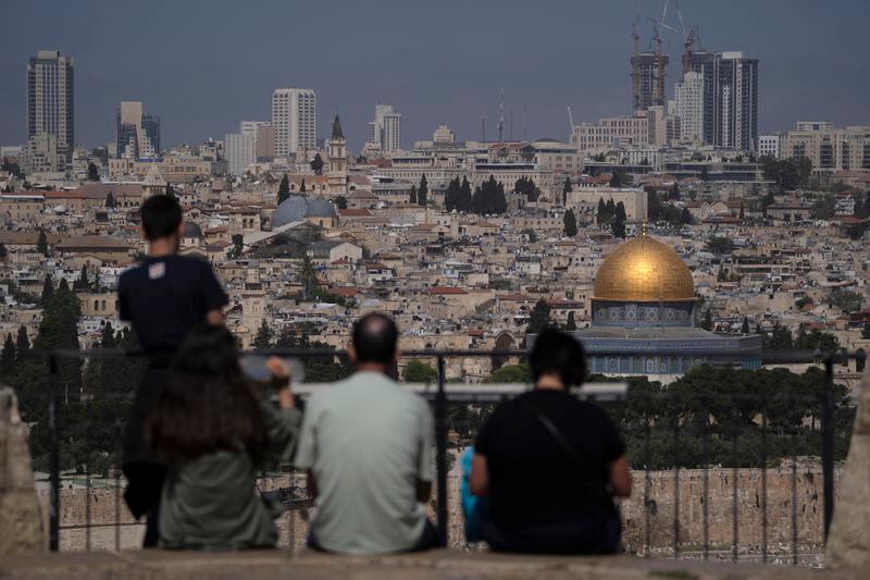 People visit the Mount of Olives overlooking the Dome of the Rock at the Al Aqsa Mosque compound in the Old City of Jerusalem, Friday, April 19, 2024. Tensions have been high since the Saturday assault on Israel amid its war on Hamas in the Gaza Strip and its own strikes targeting Iran in Syria. (AP Photo/Leo Correa)