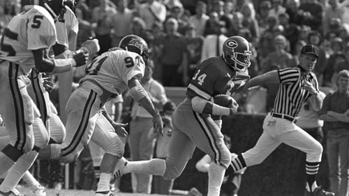 Georgia tailback Herschel Walker pulls away from Memphis State  tacklers in their game in Athens on Oct. 30, 1982. Georgia won 34-3.. (AJC file photo)