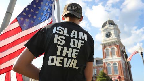 A young man stands across from the Covington courthouse during a protest organized by the III% Georgia Security Force against building a mosque in Newton County held on the town square, Tuesday, Sept. 13, 2016, in Covington. Curtis Compton /ccompton@ajc.com