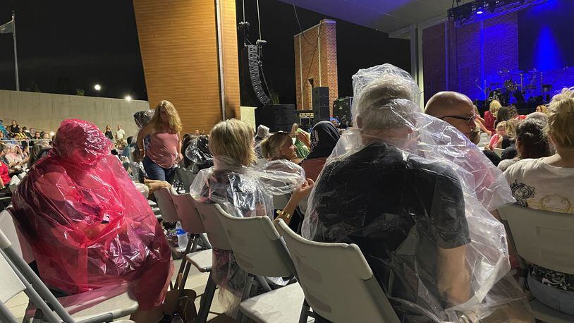Fans of Rick Springfield and Men at Work wear rain gear as they await an Aug. 6 outdoor concert in Stockbridge. The event was canceled midway through the concert because of lightning and rain. (Photo: Leon Stafford / AJC)