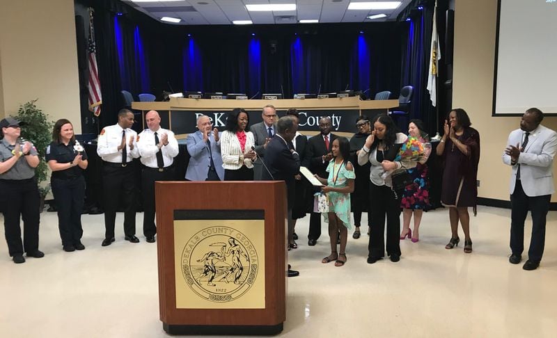 DeKalb County CEO Michael Thurmond presents a proclamation to Jayla Dallis, a 10-year-old girl credited with saving her sister from a near-drowing. Her mom Daneshia Dallis dabs away tears as school system officials, public safety officers and county commissioners applaud. TIA MITCHELL/TIA.MITCHELL@AJC.COM