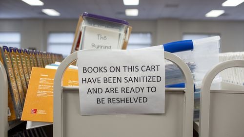 Sanitized books wait to be reshelved in Northbrook Middle School in Suwanee, Georgia, earlier this month. Gwinnett County Public Schools, the state’s largest system, had planned to reopen its buildings to students on Aug. 12 but now is going fully digital to start off. REBECCA WRIGHT FOR THE ATLANTA JOURNAL-CONSTITUTION