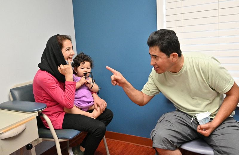 June 24, 2022 Clarkston - Ahmad Farid Frotan (right) explains the need of dental care for him and his wife Rahima Rahimi as she holds their 1-year-old daughter Sosan at Ethne Health Clinic in Clarkston on Friday, June 24, 2022. The medical practitioners at Ethne Health, a Clarkston community clinic, say many of their patients suffer from oral health problems.  (Hyosub Shin / Hyosub.Shin@ajc.com)