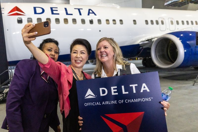 Delta employees Rebecca Yosseph (L), Lee Shreve, and Kim Bosma (R) take a selfie in front of the Delta Air Lines jet before a ceremony that revealed the plane dedicated to the Braves World Series championship Thursday, July 28, 2022. (Steve Schaefer / steve.schaefer@ajc.com)