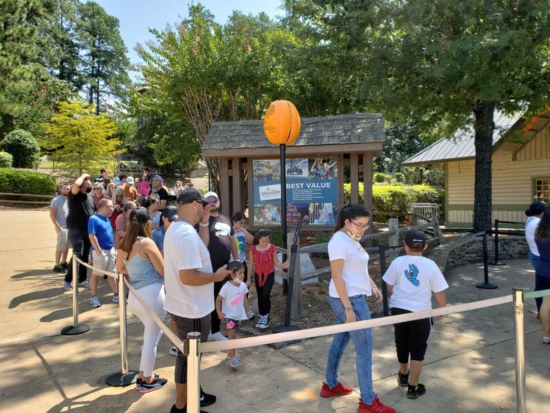 Visitors, some wearing masks, many not, stand on line near each other at the Crossroads ticket plaza at Stone Mountain Park on Labor Day weekend on Sunday, Sept. 6, 2020. MATT KEMPNER / AJC
