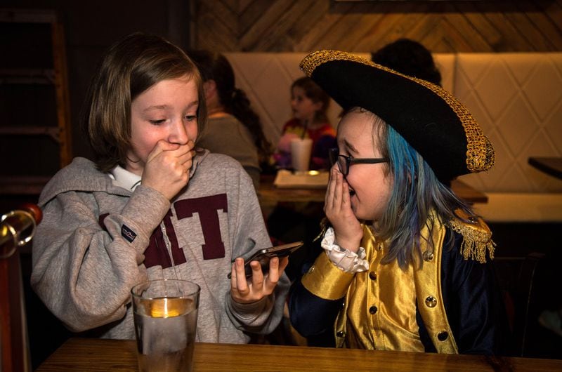 Lily Smith (left) and A.J. Marshall listen to the lyrics of the song they are planning to sing during the recent Hamiltunes ATL all-ages sing-through at the Vista Room. CONTRIBUTED BY STEVE SCHAEFER