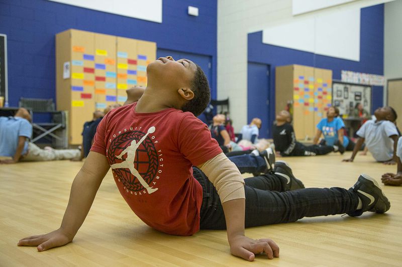 Harper-Archer Elementary School second grader Jacquez Slaton stretches his body alongside his peers at the start of dance class with dance teacher Lisa Perrymond inside the school's dance studio, Wednesday, January 29, 2020. Perrymond starts each class with deep breathing and extensive stretching. (ALYSSA POINTER/ALYSSA.POINTER@AJC.COM)