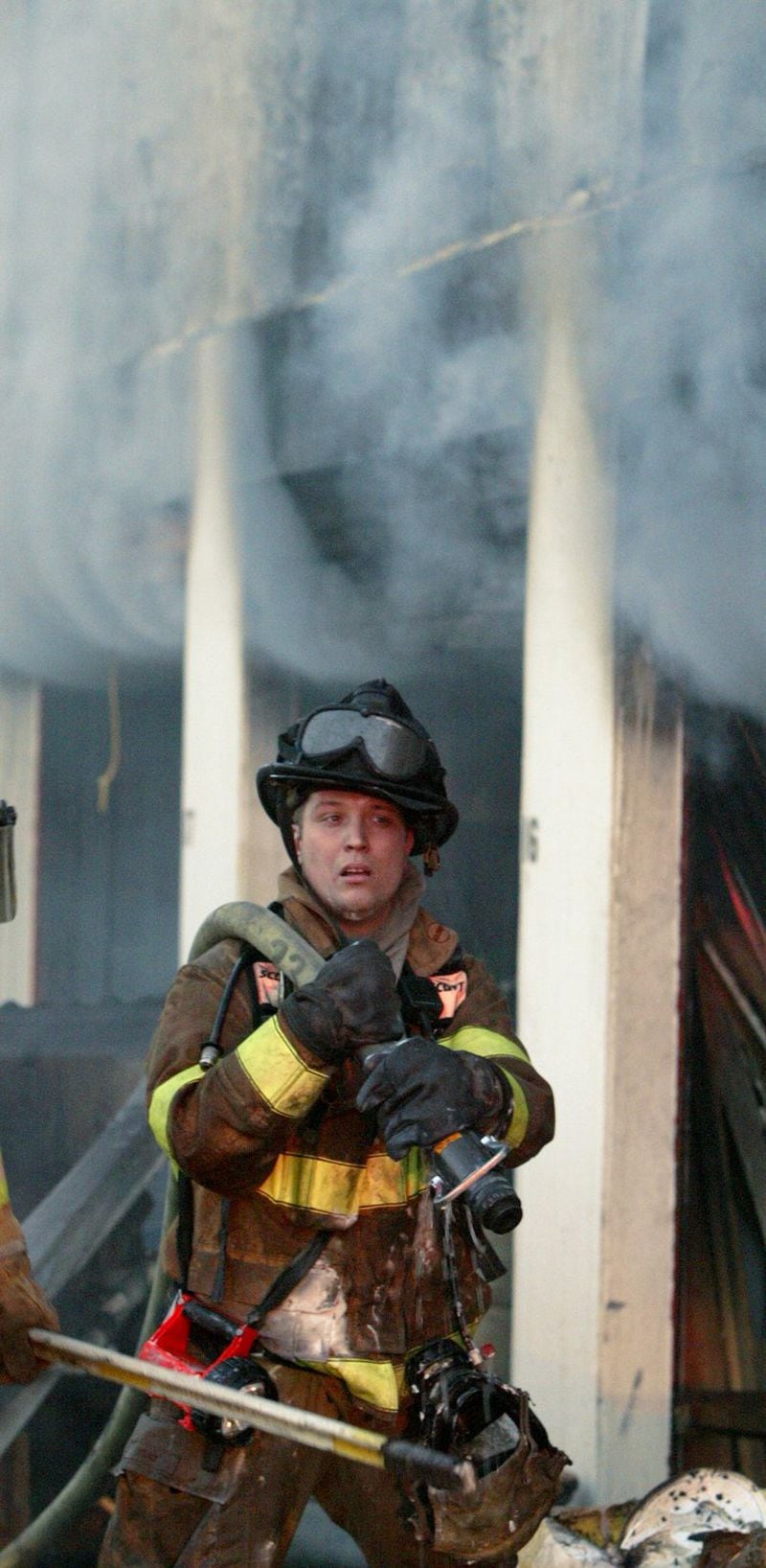A 2004 file photo shows Chris Coons as an Atlanta firefighter hauling hose to fighting a stubborn storage facility fire in the 1300 block of Northside Drive. (JOHN SPINK/AJC staff)