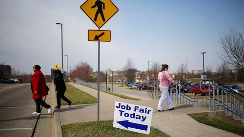 Pedestrians pass in front of signage displayed outside a Job News USA career fair in Overland Park, Kansas, U.S., on March 8, 2017. MUSTS CREDIT: Bloomberg photo by Luke Sharrett.