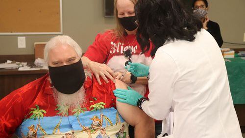 "Santa" Teddy Jackson is assisted by his wife Vicki Jackson as Cobb and Douglas Public Health Director Dr. Janet Memark gives him his COVID-19 vaccine. The Jacksons are among the founders of Peachtree Santas. (Courtesy of Cobb County)